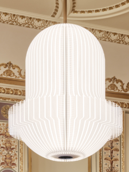 Heller Veranstaltungsraum mit aufwendig verzierter Stuckdecke in Weiß und Gold, rotem Teppichboden und mehreren runden Bistrotischen mit schwarzen Stühlen. An der rechten Seite befindet sich eine dunkle Bartheke. Eine große weiße Pendelleuchte hängt zentral von der Decke. Der Raum wirkt durch große Wandspiegel und hohe Fenster großzügig und repräsentativ. 